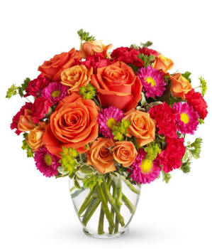 Illinois Floral arrangement featuring light orange roses, orange spray roses, hot pink carnations, and matsumoto asters in a clear glass vase.